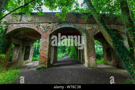 Una vista lungo la ferrovia in disuso via attraverso il ponte stradale a South Cerney nel Cotswold Water Park, Inghilterra Foto Stock