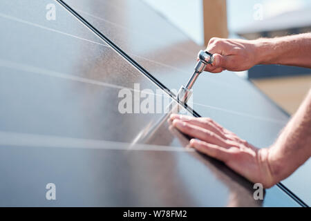 Le mani del maestro contemporaneo con la vite di regolazione o di installare pannelli solari Foto Stock