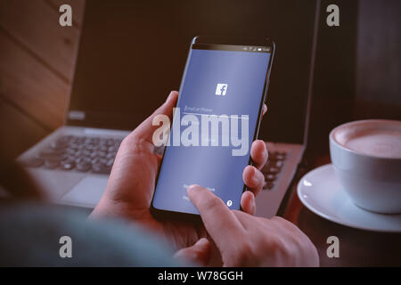 Bangkok, Tailandia - 5 Agosto 2019: una donna possiede uno smartphone e accedi con Facebook Application sullo schermo. Facebook è un popolare social media Foto Stock