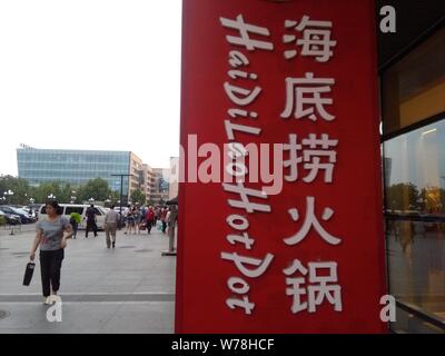 --FILE--pedoni a piedi passato un cartello di Hai di Lao Hotpot a Pechino, in Cina, il 28 maggio 2016. Haidilao Hotpot, il ristorante della catena che porta il Foto Stock