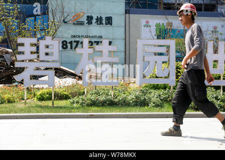 --FILE--un lavoratore cinese passeggiate passato un cartello di cinesi immobiliare Country Garden nella città di Dalian, a nord-est della Cina di provincia di Liaoning, 7 Foto Stock