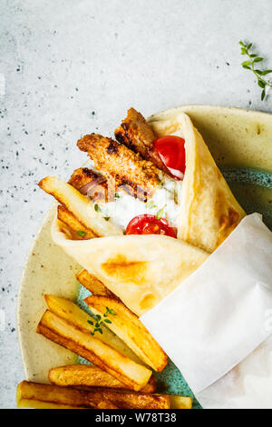 Gyros souvlaki avvolge in pane pita con pollo, patate e salsa tzatziki, copia dello spazio. Foto Stock