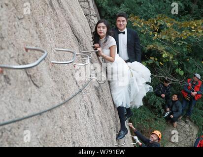 Una sposa giovane cinese pone per foto di nozze appesa a una scogliera del Chaya Mountain scenic spot in città Zhumadian, centrale della Cina di gallina Foto Stock
