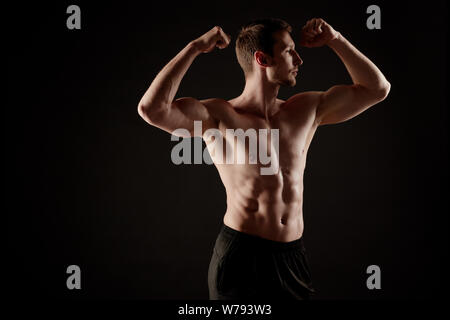 Uomo muscolare con shirt off mostra il suo corpo alla telecamera. Foto Stock