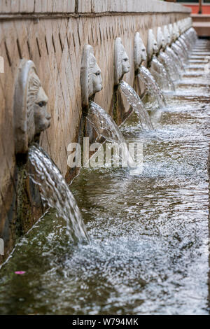 Teste leone che sgorgano acqua in un lungo canale è una fontana veneziana nella città di Spili, Creta, Grecia Foto Stock