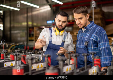 Due giovani uomini di controllo industriale di nuove apparecchiature di elaborazione Foto Stock