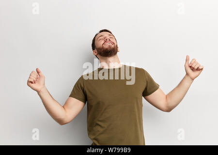 Giovane uomo eccitato con i bracci sollevati cercando. vinner celebra il suo successo. close up photo isolati a sfondo bianco. studio shot Foto Stock