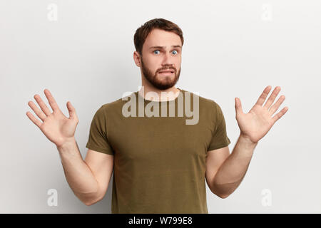 Emotional giovane uomo in verde t-shirt con le mani alzate fino proteggere se stesso. close up foto. Paura, fobia isolati a sfondo bianco Foto Stock