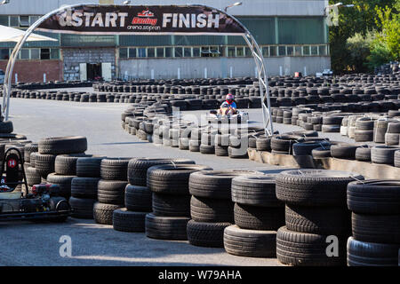 Go-kart passando accanto iniziare e terminare il banner tra barriere di pneumatici Foto Stock