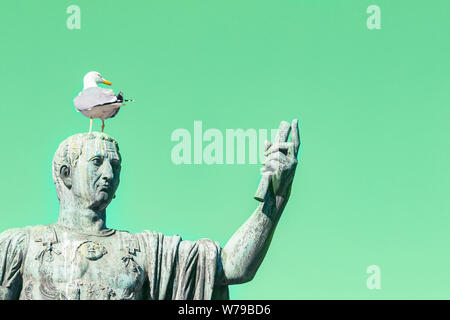 Statua di imperatore Cesare Nervae Agosto con gabbiano sulla testa. L'uomo prendendo selfie. Concetto di umorismo. Verde menta sfondo Foto Stock