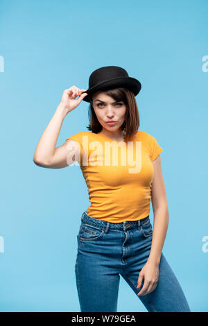 Giovane donna informale in black hat, giallo t-shirt e jeans blu Foto Stock