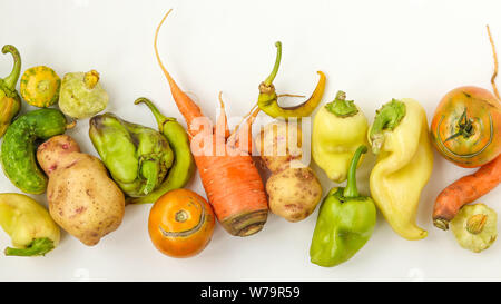 Alla moda di brutto ortaggi: patate, carote, cetrioli, peperoni e pomodori su sfondo bianco, brutto concetto alimentare, vista dall'alto, orientamento orizzontale Foto Stock