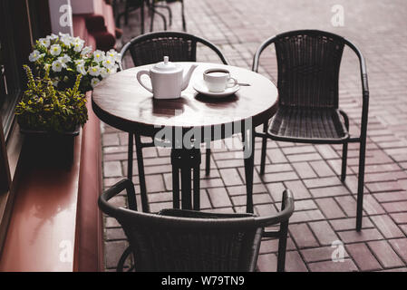 Vista sulla strada di una terrazza estiva cafe con tavolo e sedie. Foto Stock