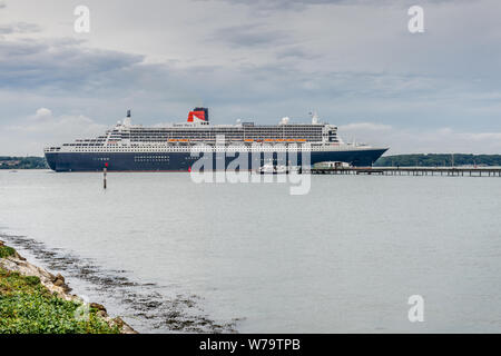 La RMS Queen Mary 2 crociera / nave da crociera (QM2) passato a vela Hythe Pier dopo aver lasciato il porto di Southampton in Hampshire, Inghilterra, Regno Unito Foto Stock