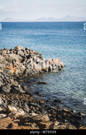 Il paesaggio costiero in Playa Blanca sull isola di Lanzarote con Fuerteventura in background Foto Stock