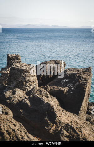 Paesaggio roccioso in Playa Blanca sull isola di Lanzarote con Fuerteventura in background Foto Stock