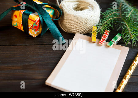 Preparazione per il natale - Blocco note per creare un elenco di regali per amici e familiari sullo sfondo di legno Foto Stock