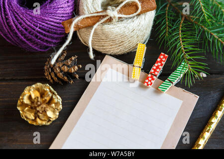 Preparazione per il natale - Blocco note per creare un elenco di regali per amici e familiari sullo sfondo di legno Foto Stock