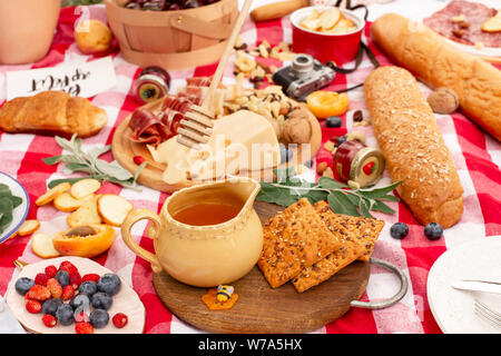 Elegante pic nic sul prato verde. Cornetti freschi e una teiera con il tè su un copriletto vicino a una femmina di vimini hat. Instagram contenuto. Foto Stock