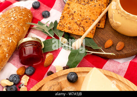 Elegante pic nic sul prato verde. Cornetti freschi e una teiera con il tè su un copriletto vicino a una femmina di vimini hat. Instagram contenuto. Foto Stock
