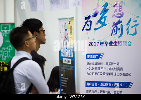 Laureati cinesi e persone in cerca di lavoro guardare un annuncio pubblicitario per il reclutamento del personale a una fiera del lavoro nella città di Shenzhen, Cina del sud della provincia di Guangdong, 16 Octobe Foto Stock