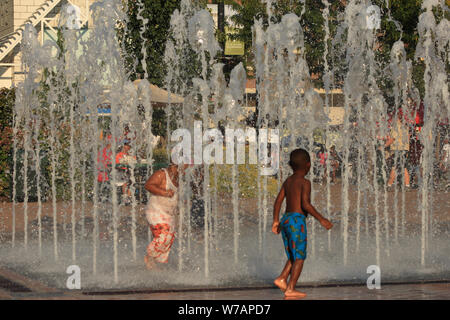 Bambini godendo interactive fontane ad acqua in estate Foto Stock