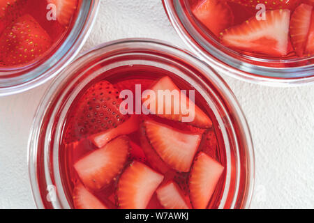 Gelatina di fragole con fragole a fette in una ciotole in vetro direttamente dal di sopra, Close Up su bianco Foto Stock