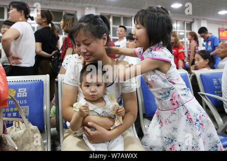 --FILE--una ragazza cinese gioca con la sua madre che trattiene la sorella più giovane come loro di attendere presso la Xiangyang Stazione Ferroviaria di Xiangyang city, Chi centrale Foto Stock