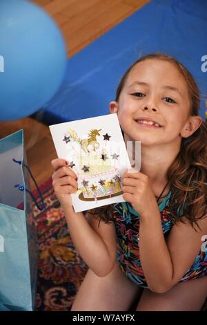 Settimo compleanno ragazza con carta che ha una unicorn su di esso Foto Stock