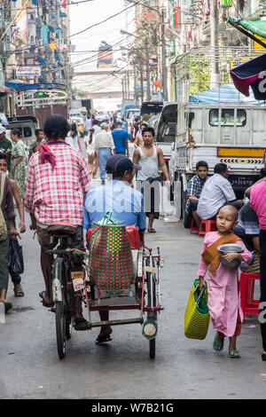 Yangon, Myanmar-May 4° 2014: una strada trafficata nel centro della citta'. Rickshaws sono ancora usati comunemente. Foto Stock