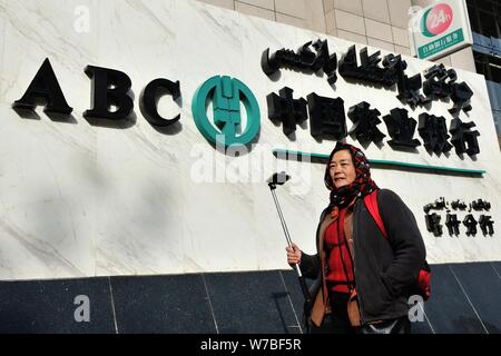 --FILE--un residente locale passeggiate passato una filiale della Banca agricola di Cina (ABC) nella città di Kashgar, a nord-ovest della Cina di Xinjiang Uyghur Regione autonoma, Foto Stock