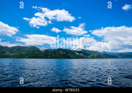 Montenegro, montagne verdi al fianco di costa del lago di Lago di Skadar acque visto dalla barca nel parco nazionale Foto Stock