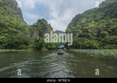 Tam Coc, Vietnam. Il 6 agosto 2019. Quando la temperatura raggiunge 35 gradi i boat people del fiume Ngo Dong preparatevi al traghetto popolo profondo in montagna, in quello che viene descritto come il Halong Bai su terra, raffreddare in una delle tante grotte che copre la zona . Credito: Paolo Quezada-Neiman/Alamy Live News Foto Stock