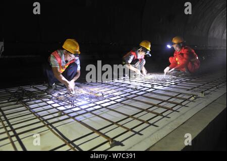 Lavoratori cinesi del lavoro ballastless via presso il cantiere per la costruzione di un tunnel lungo la ferrovia Chengdu-Guiyang nel sud-ovest della Cina di Sichuan pro Foto Stock