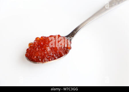Caviale rosso in un cucchiaio closeup su sfondo bianco Foto Stock