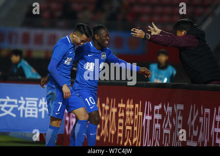 Calcio camerunese player Bassogog Cristiana di Henan Jianye, centro celebra con il suo compagno di squadra Hu Jinghang e i loro coach Guo Guangqi dopo aver sco Foto Stock