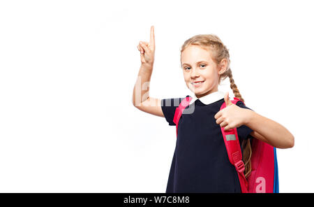 Allegro 8 anni schoolgirl con zaino indossano uniformi isolato permanente su sfondo bianco. Pronti per la scuola Foto Stock