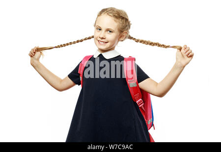 Allegro 8 anni schoolgirl con zaino indossano uniformi isolato permanente su sfondo bianco. Pronti per la scuola Foto Stock