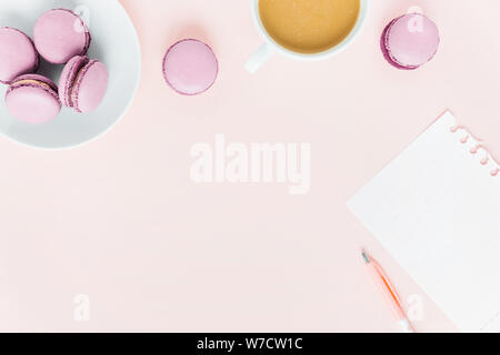 Sfondo rosa con amaretti e una tazza di tè circondato da le peonie. Vista dall'alto. Foto Stock