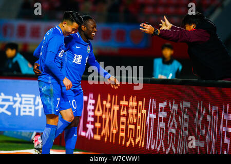 Calcio camerunese player Bassogog Cristiana di Henan Jianye, centro celebra con il suo compagno di squadra Hu Jinghang e i loro coach Guo Guangqi dopo aver sco Foto Stock