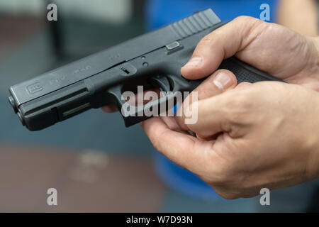 Una mano di uomo praticando la cottura utilizzando una pistola Glock modello presso il poligono di tiro. Fire glock a pistola. Foto Stock