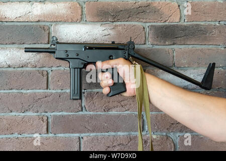 PP-91 Kedr mitragliatore. Un uomo tiene un fucile in mano sullo sfondo di un marrone un muro di mattoni. Foto Stock