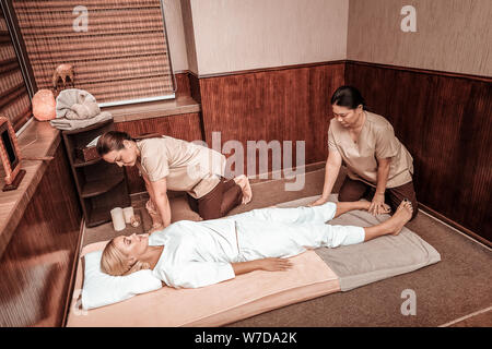 Due donne facendo massaggi per i loro client. Foto Stock