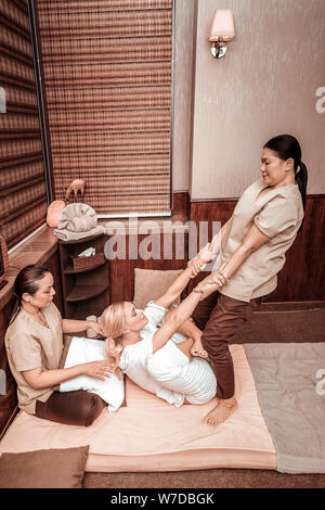 Due donne facendo del massaggio thailandese per il loro cliente. Foto Stock