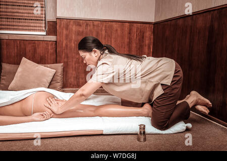 Massaggiatrice facendo glutei massaggi per il suo cliente. Foto Stock