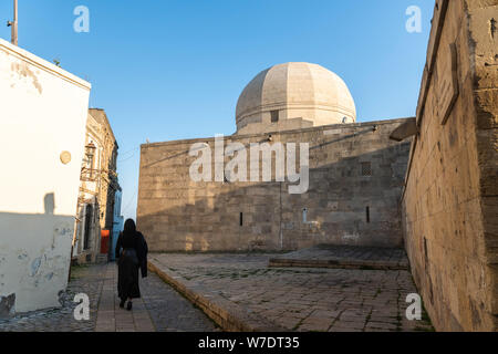 Street view nel Icherisheher città vecchia di Baku, in Azerbaijan, con la parete esterna del Palazzo di Shirvanshahs edificio e identificabili in figura Foto Stock