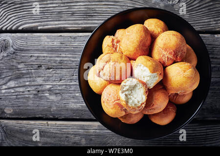 Caraibi fritto gnocchi azzimo in una ciotola nero su un vecchio rustico in legno tabella, vista orizzontale dal di sopra, close-up, flatlay Foto Stock