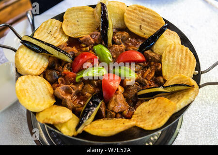 In padella sac piatto con carne e verdure, funghi e patate servita su una piastra calda a induzione a un ristorante in Azerbaigian. Foto Stock