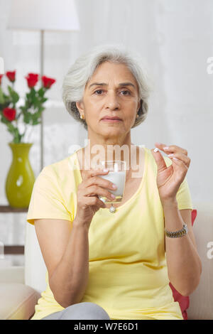 Vecchia donna prendendo medicine Foto Stock