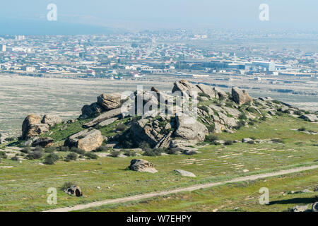 Paesaggio in Kichikdash area di Gobustan, Azerbaigian, con pile di boulder e di Gobustan insediamento in background. Foto Stock